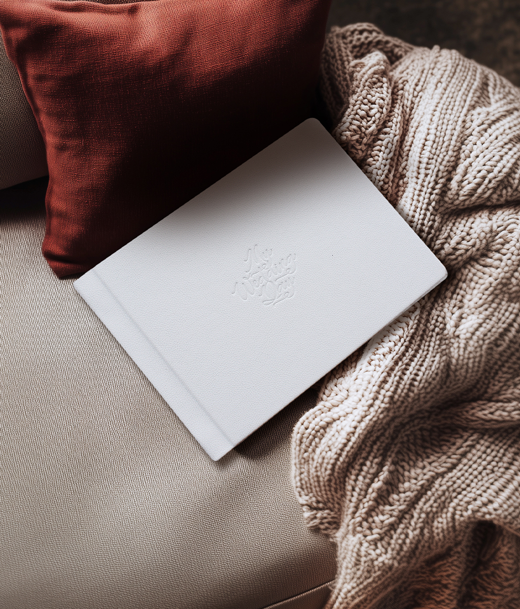 hardcover leathertte photo book with taupe color on a leather couch with a drap of knitted blanket