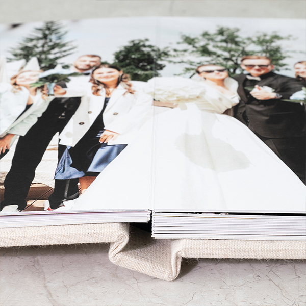 Premium linen wedding album open to a full spread wedding group portrait showcasing seamless lay flat binding