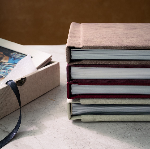 stack of premium custom wedding photo albums with luxury covers and thick pages on marble table